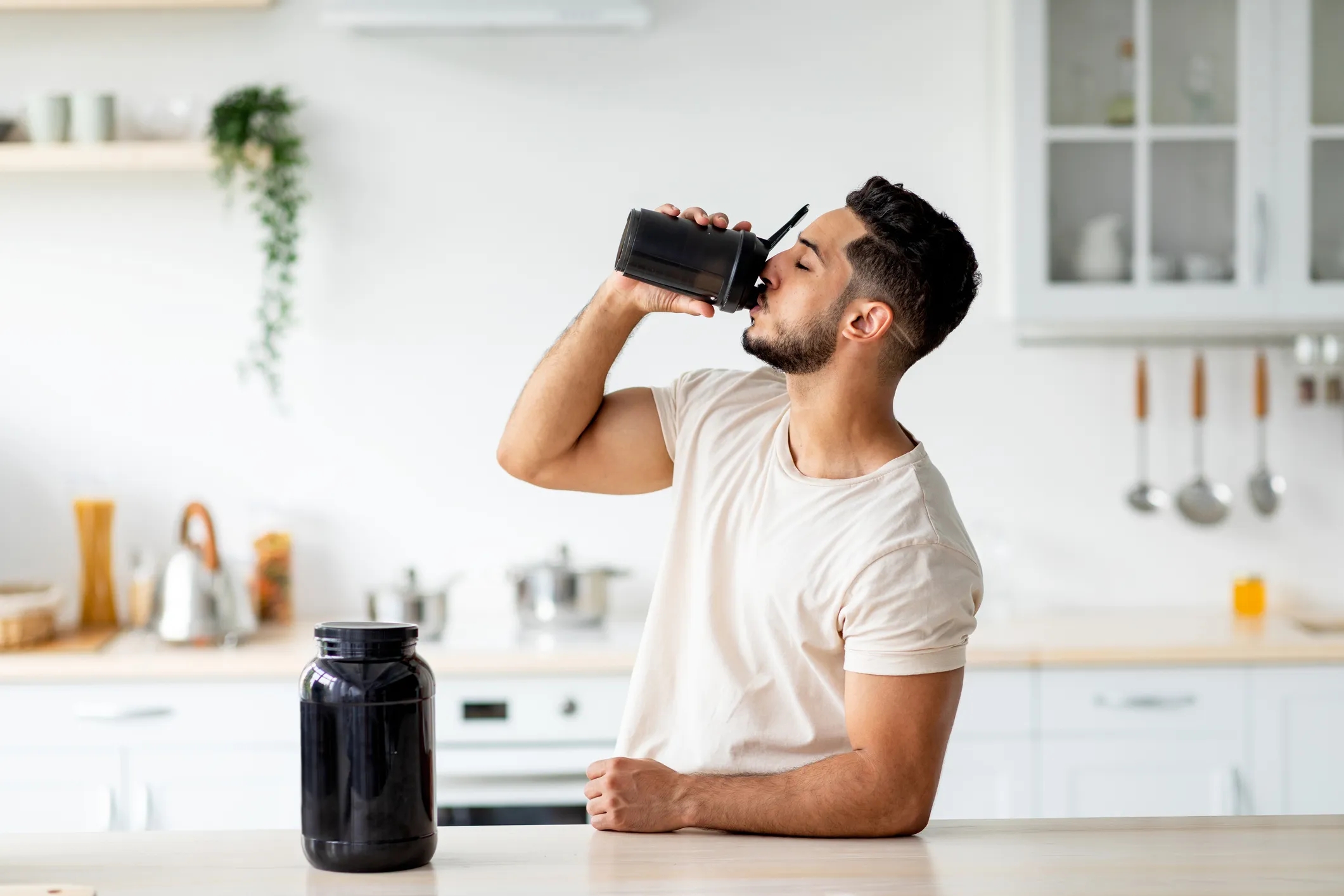 Young Arab man drinking a
protein shake from a bottle in the kitchen. The image highlights the
use of tri-potassium citrate in enhancing athletic performance and
recovery.
