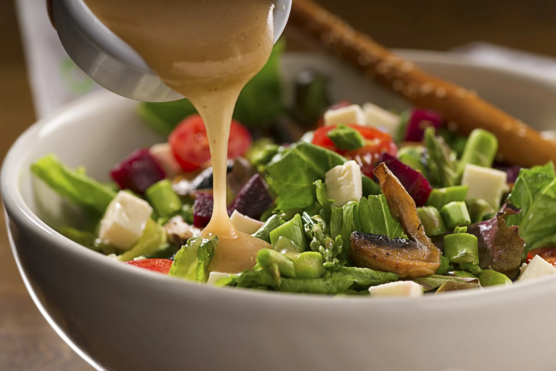 Creamy salad dressing poured over fresh vegetables, illustrating texture and stability in food applications.